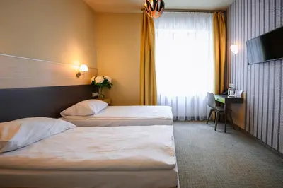 a hotel room with two beds and a television at Hotel Kazimierz III in Kraków