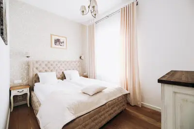 a bedroom with a bed with white sheets and a window at Premium Apartments by Wawel Castle in Kraków