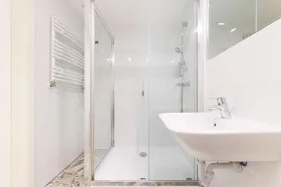 a white bathroom with a sink and a shower at Premium Apartments by Wawel Castle in Kraków