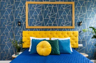 a blue bedroom with a yellow headboard and pillows at Luxe Living Krakow in Kraków
