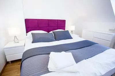 a bedroom with a large bed with a purple headboard at Apartamenty SaltApart in Wieliczka