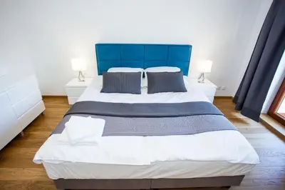 a large bed with a blue headboard in a bedroom at Apartamenty SaltApart in Wieliczka