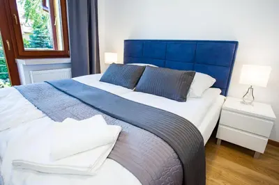 a blue and white bed in a room with a window at Apartamenty SaltApart in Wieliczka