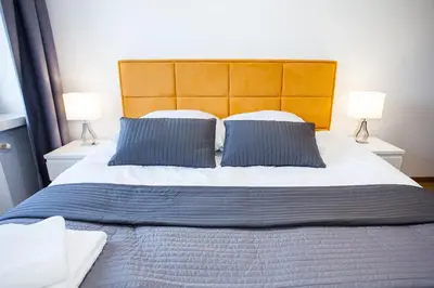 a large bed with two blue pillows and two lamps at Apartamenty SaltApart in Wieliczka