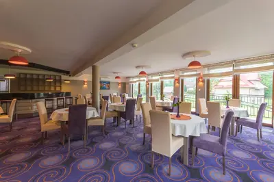a dining room with tables and chairs and windows at Beskid in Zawoja