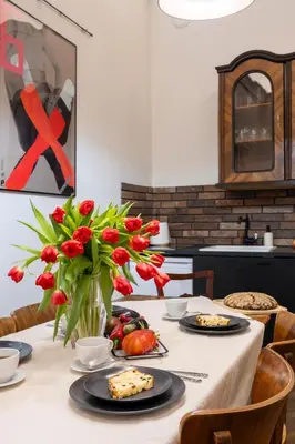 a table with plates of food and a vase of flowers at Kurkowa Apartments in Kraków