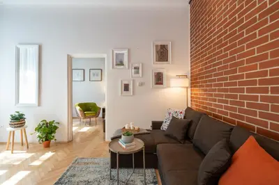 a living room with a couch and a brick wall at Sleeping in Krakow Main Market in Kraków