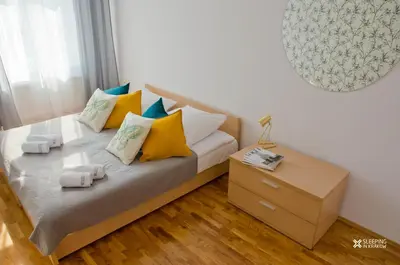 a bed with yellow and blue pillows and a night stand at Sleeping in Krakow Main Market in Kraków