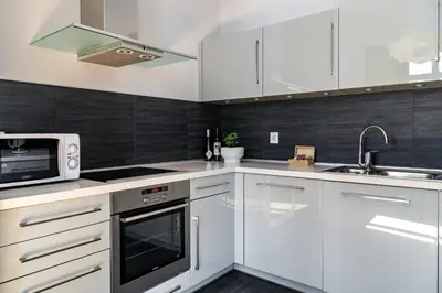 a white kitchen with a microwave and a sink at Yourplace Biskupia Old Town Apartments in Kraków