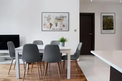 a dining room with a white table and gray chairs at Yourplace Biskupia Old Town Apartments in Kraków