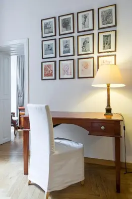 a desk with a chair and a lamp and pictures on the wall at Yourplace Biskupia Old Town Apartments in Kraków