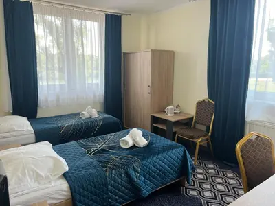 a hotel room with two beds and a chair at Hotel Vistula in Kraków