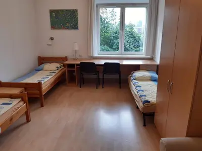a room with two beds and a desk and a window at Salwator Apartments in Kraków