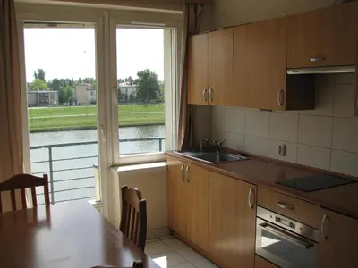 a kitchen with a table and a view of the water at Salwator Apartments in Kraków