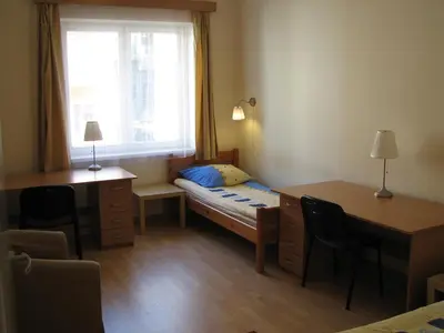a small room with a bed and a desk and a window at Salwator Apartments in Kraków