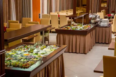 a row of buffet tables with plates of food at Hotel Great Polonia Conrad Kraków in Kraków