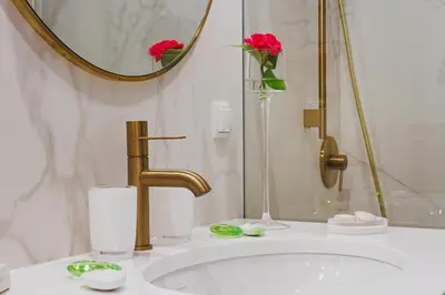 a bathroom sink with a gold faucet and red flowers at Apartamenty Bracka 6 in Kraków