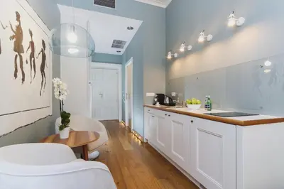 a kitchen with white cabinets and a table at Apartamenty Bracka 6 in Kraków