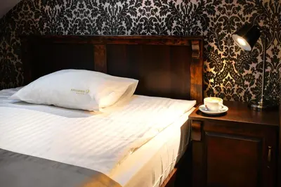 a bed with a white pillow and a cup on a table at Residence 9 in Kraków