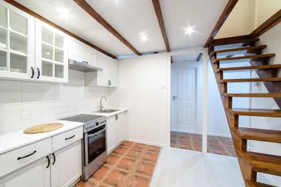 a kitchen with white cabinets and a spiral staircase at Cracow Rent Apartments - spacious apartments for 2-7 people in quiet area - Kolberga Street nr 3 - 10 min to Main Square by foot in Kraków