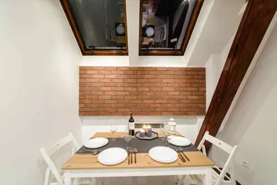a dining room table with white plates and a bottle of wine at Cracow Rent Apartments - spacious apartments for 2-7 people in quiet area - Kolberga Street nr 3 - 10 min to Main Square by foot in Kraków