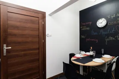 a dining room with a table and a clock on a wall at Cracow Rent Apartments - spacious apartments for 2-7 people in quiet area - Kolberga Street nr 3 - 10 min to Main Square by foot in Kraków