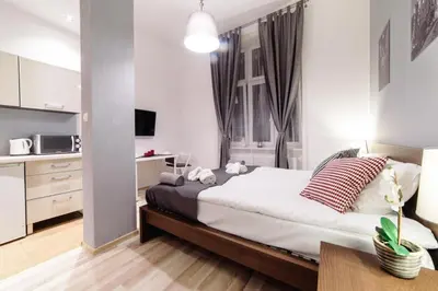 a bedroom with a large bed and a kitchen at Cracow Rent Apartments - spacious apartments for 2-7 people in quiet area - Kolberga Street nr 3 - 10 min to Main Square by foot in Kraków