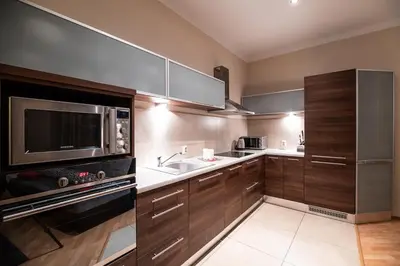 a kitchen with wooden cabinets and a sink and a microwave at Cracow Rent Apartments - spacious apartments for 2-7 people in quiet area - Kolberga Street nr 3 - 10 min to Main Square by foot in Kraków