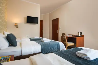 a hotel room with two beds and a desk at Aparthotel Globus Self-Check in in Kraków