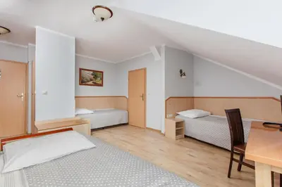 a bedroom with two beds and a desk and a table at Antica Residence in Kraków