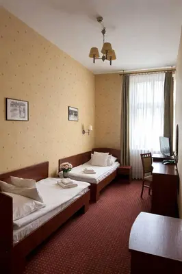 a hotel room with two beds and a desk and a mirror at Aneks Hotelu Kazimierz in Kraków