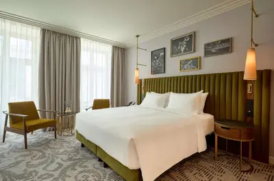 a hotel room with a bed and a desk and chairs at Hotel Saski Krakow Curio Collection by Hilton in Kraków