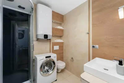 a bathroom with a washing machine and a toilet at Old Town Luxe Retreat - King Bed - Steps to Main Square in Kraków