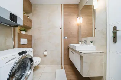 a bathroom with a washing machine and a sink at Old Town Luxe Retreat - King Bed - Steps to Main Square in Kraków