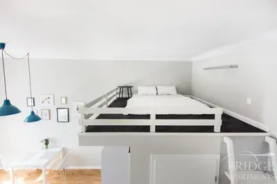 a white bedroom with a white bed and a desk at Bridge Apartments in Kraków