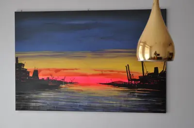 a painting of a sunset over the water at Bridge Apartments in Kraków