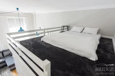 a bedroom with a white bed with a black rug at Bridge Apartments in Kraków
