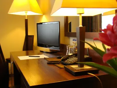 a desk with a computer monitor and a keyboard and a lamp at Hotel Azalia & Spa in Niepołomice