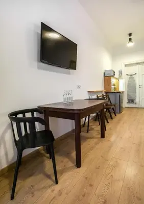 a wooden table with a chair and a television on a wall at Pokoje Gościnne Św. Anny in Kraków