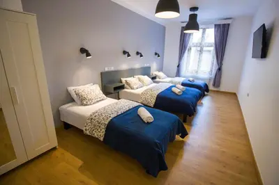 three beds in a room with blue sheets and pillows at Pokoje Gościnne Św. Anny in Kraków
