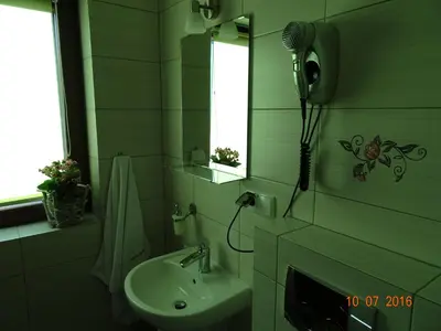 a green bathroom with a sink and a mirror at ZłotyOgród in Wieliczka