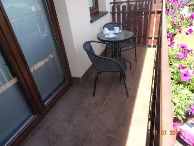 a small table and chairs on a balcony with flowers at ZłotyOgród in Wieliczka
