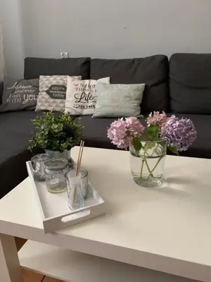 a white coffee table with flowers on a couch at Apartment Oświęcim klimatyzowany in Oświęcim