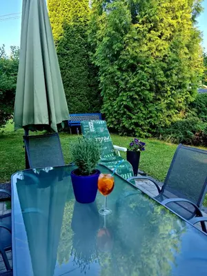 a glass table with an umbrella and a drink on it at Forest House in Lubomierz