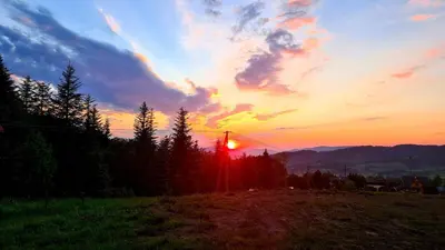 a sunset in a field with the sun setting at Forest House in Lubomierz