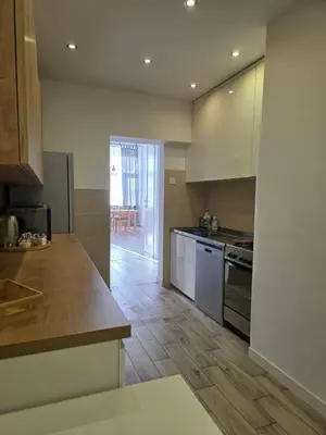 a kitchen with white appliances and a wooden floor at Apartament Vistula in Kraków