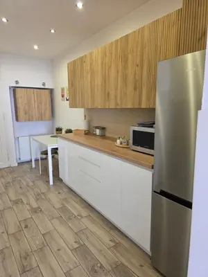a kitchen with white cabinets and a stainless steel refrigerator at Apartament Vistula in Kraków