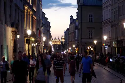 a crowd of people walking down a street at night at AR Apartments - Angel Center Kraków in Kraków