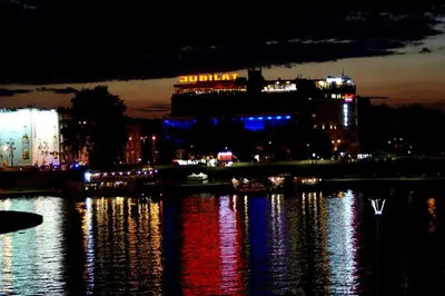 a night view of a building with lights on the water at AR Apartments - Angel Center Kraków in Kraków