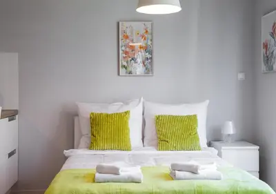 a bedroom with a large bed with two green pillows at AR Apartments - Angel Center Kraków in Kraków